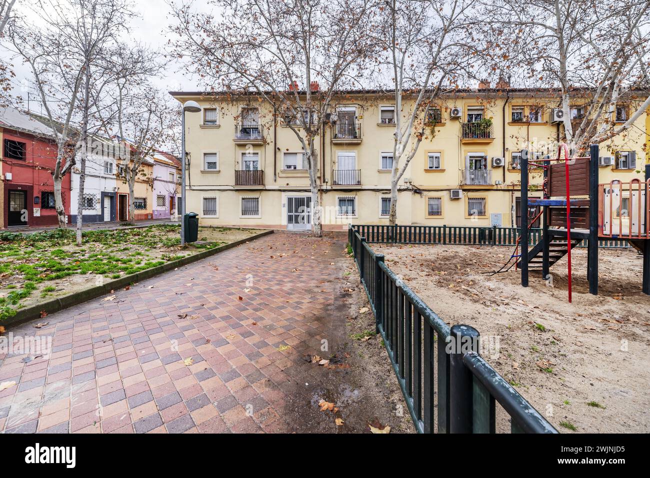 Fassaden flacher Stadthäuser auf einem großen Platz mit Kinderspielplätzen mit Sandböden Stockfoto