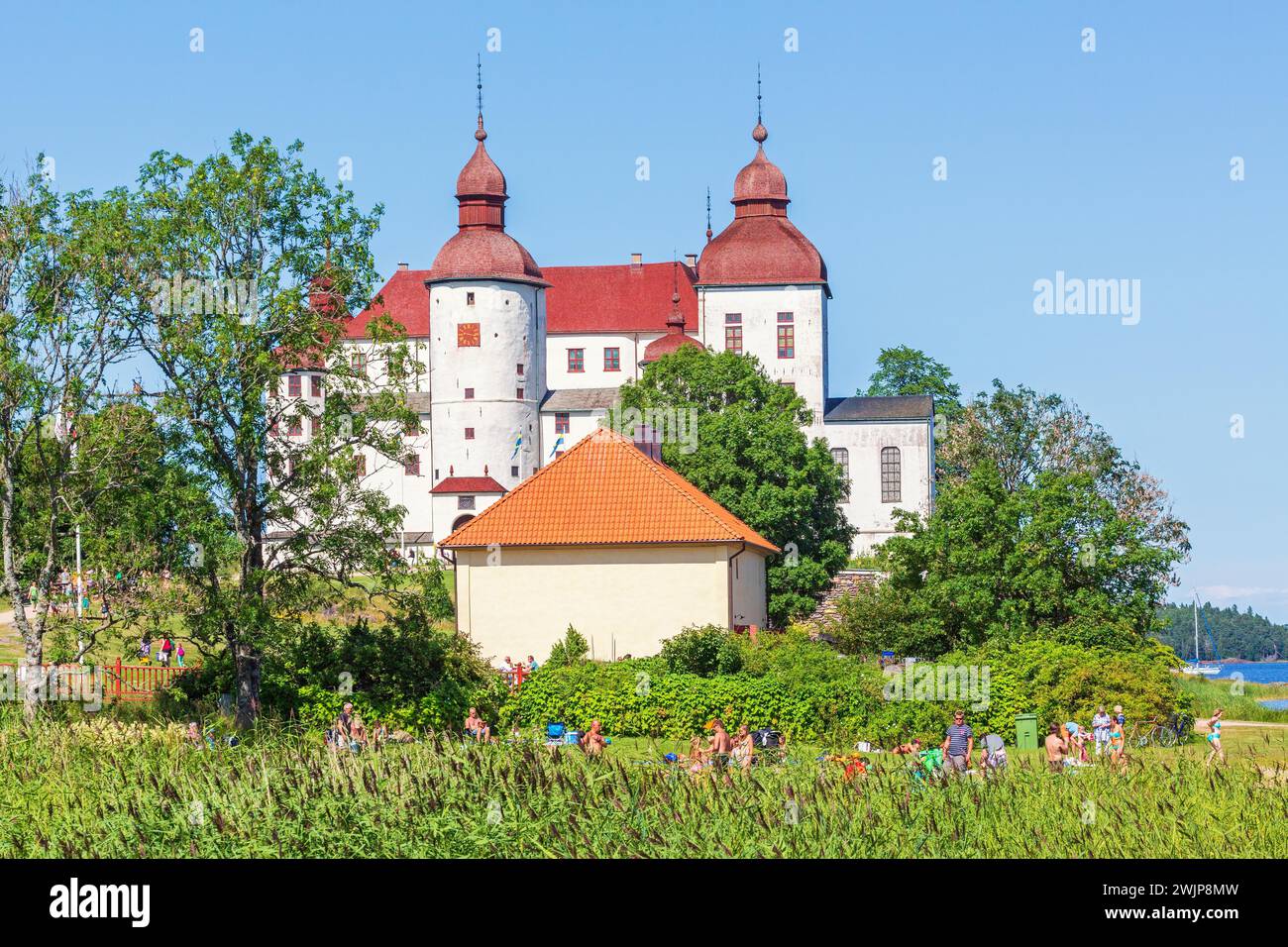 Schloss Laeckoe, ein schwedisches Barockschloss mit Menschen an einem Badeplatz am See Vaenern im Sommer, Laeckoe, Lidkoeping, Schweden Stockfoto