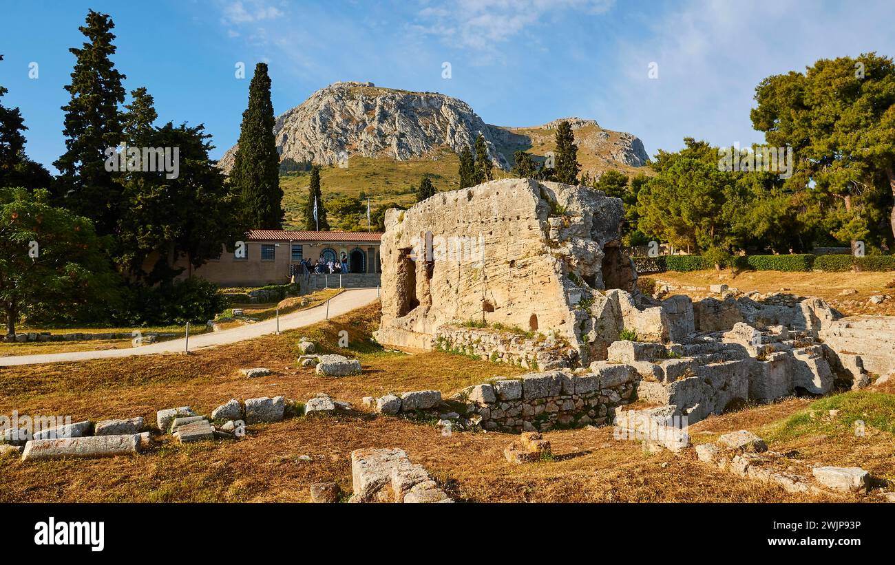 Alte zerbröckelnde Mauern einer archäologischen Stätte mit Bäumen und Bergen im Hintergrund, archäologische Stätte, Archea Korinthos, Korinth Stockfoto