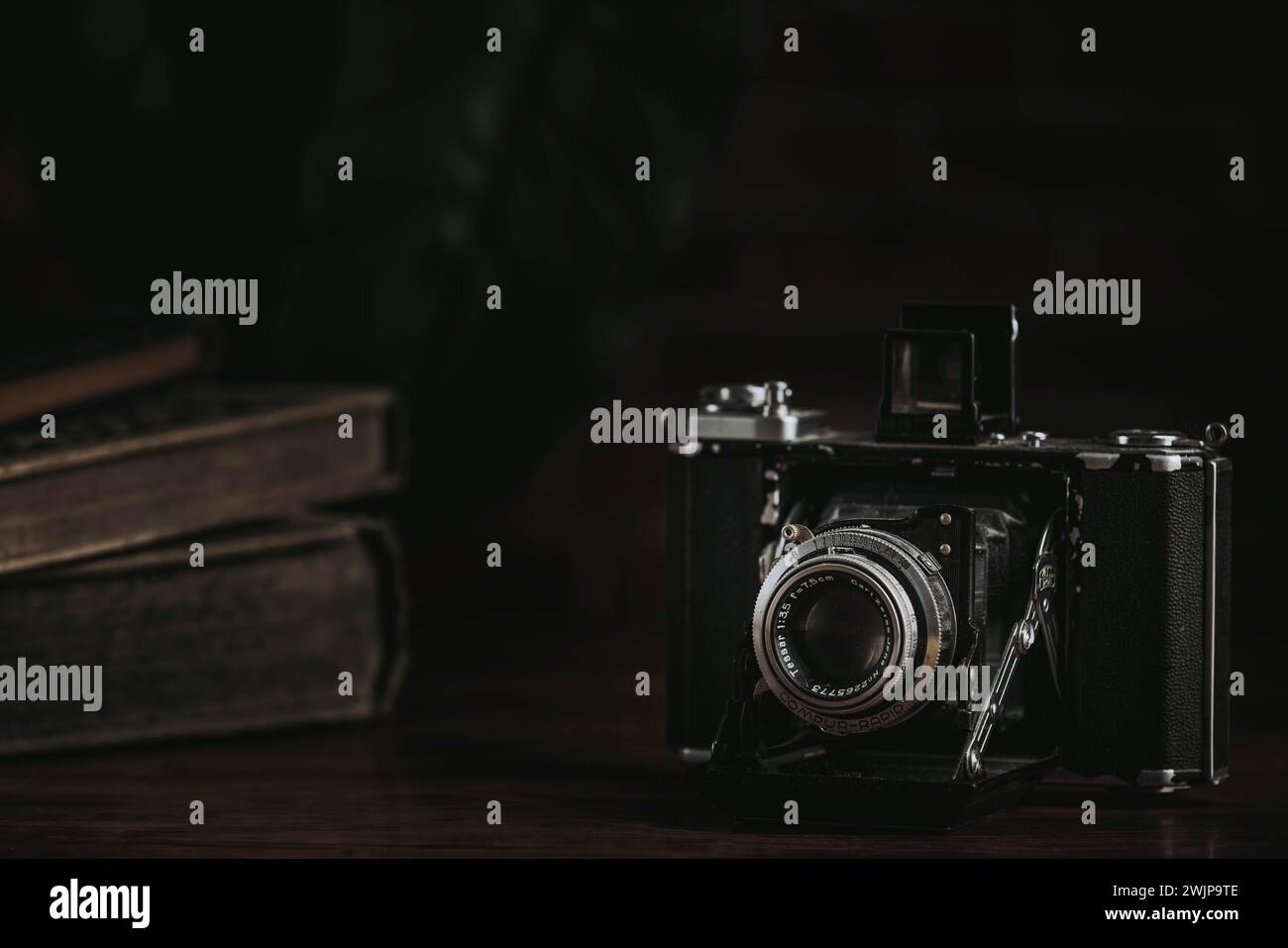 Alte Kamera auf dunklem Hintergrund neben alten Büchern Stockfoto