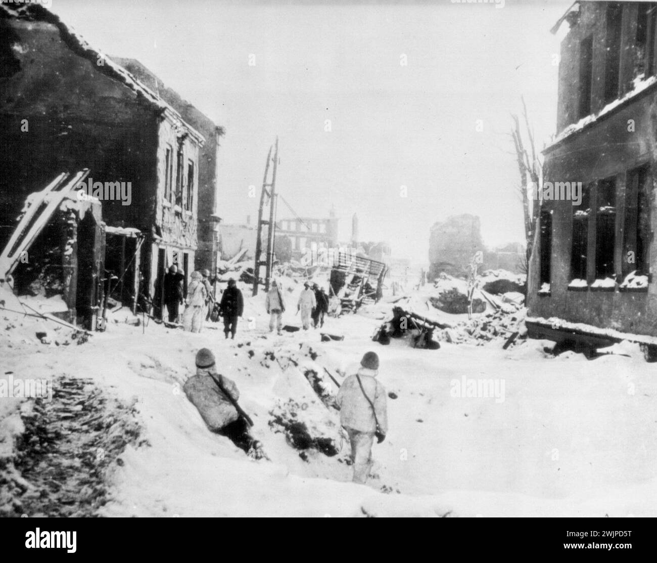 Wracked St. Vith in Schwarz und weiß -- US-Truppen der Ersten Armee, verputzt in Tarnschutzanzügen, Wiedersehen in den schneebedeckten Straßen und geschwärzten Häusern von St. Vith, Belgien, nachdem die Stadt von den deutschen Streitkräften erobert wurde. 31. Januar 1945. (Foto von AP Wirephoto). Stockfoto