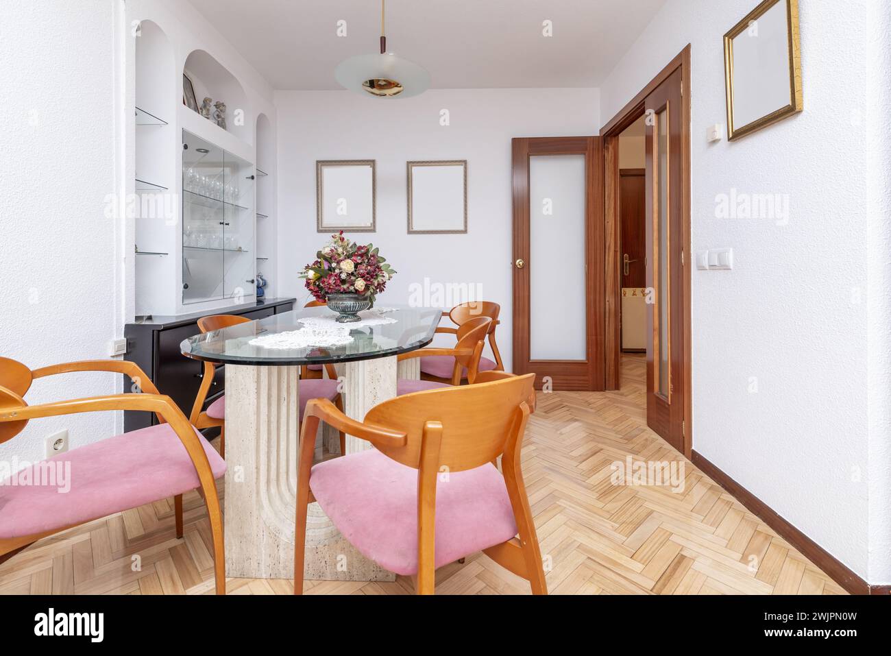 Wohnzimmer eines Hauses mit einem Glastisch mit Marmorfüßen und Kirschholzstühlen Stockfoto