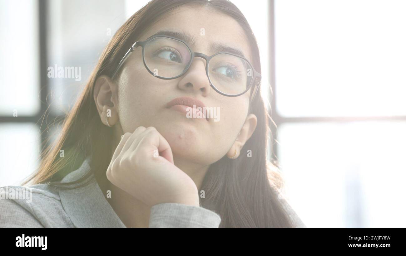 Eine junge Frau mit Brille im Büro denkt nach Stockfoto