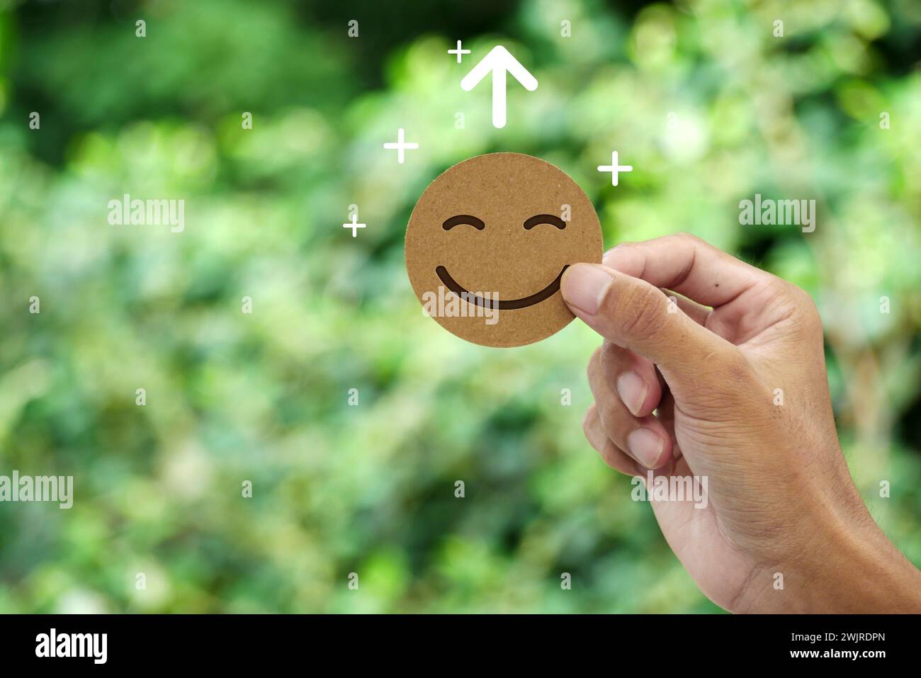 Die Hand hält Happy Smile-Gesichtskarte. Konzept des positiven Denkens, der psychischen Gesundheit, der emotionalen Erholung, der Wachstumseinstellung, der Glücksgefühle. Stockfoto