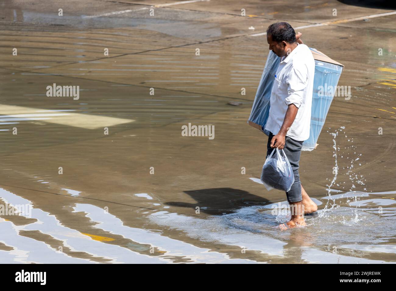 SAMUT PRAKAN, THAILAND, NOV 30 2023, Ein Mann trägt einen Sack Plastikkisten auf einer überfluteten Straße Stockfoto