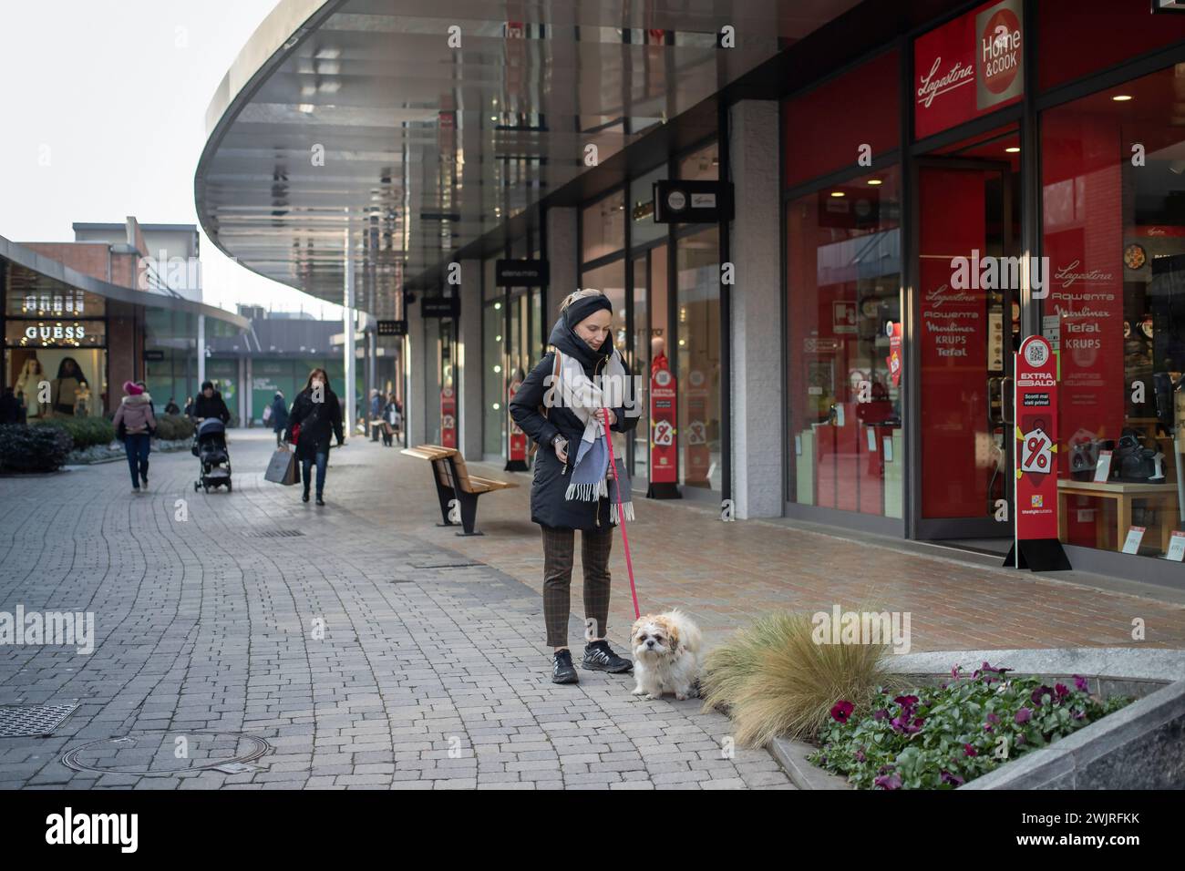 Novara, Italien, 16. Januar 2024: Frau mit Hund schlendert durch das Einkaufszentrum „Vicolungo the Style Outlets“ Stockfoto