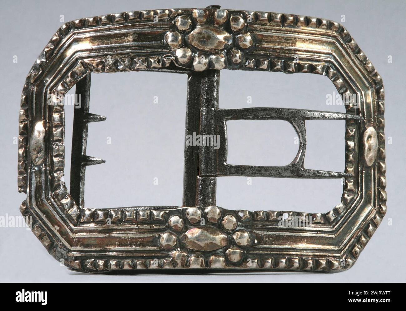 Master-Schleife. Initialen PB auf beiden Seiten eines langen Schnabels gestochen; nicht identifiziertes Zeichen. Hohlband in der Mitte, Perlenränder, 2 ovale Blütenperlen hoch und niedrig, ovale Perle in der Mitte jeder Seite. Stockfoto