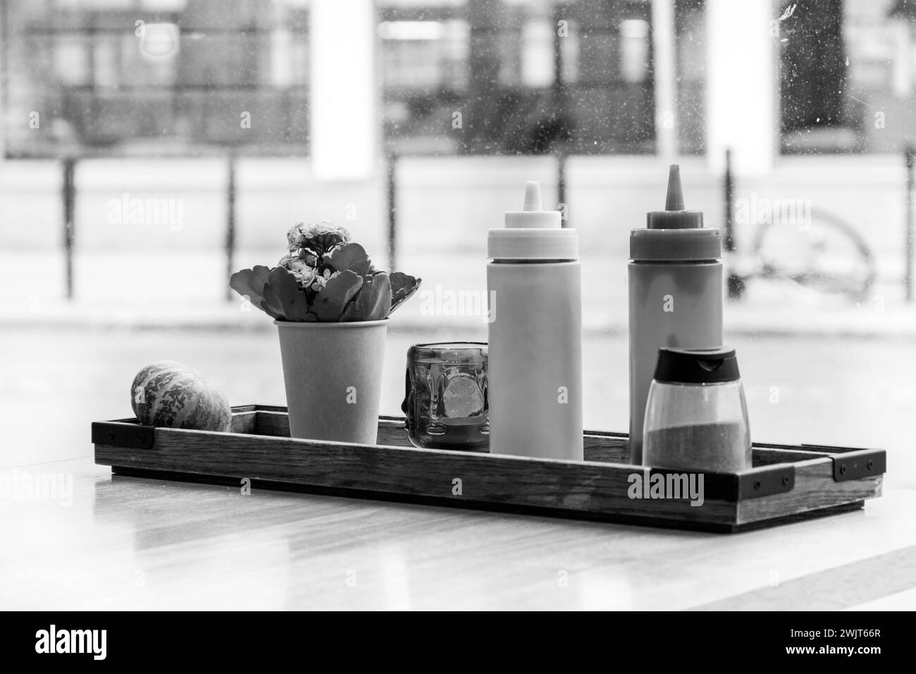 Ketchup- und Senfflaschen auf einem Tisch vor einem Fenster in einem Diner. Schwarzweißbild Stockfoto