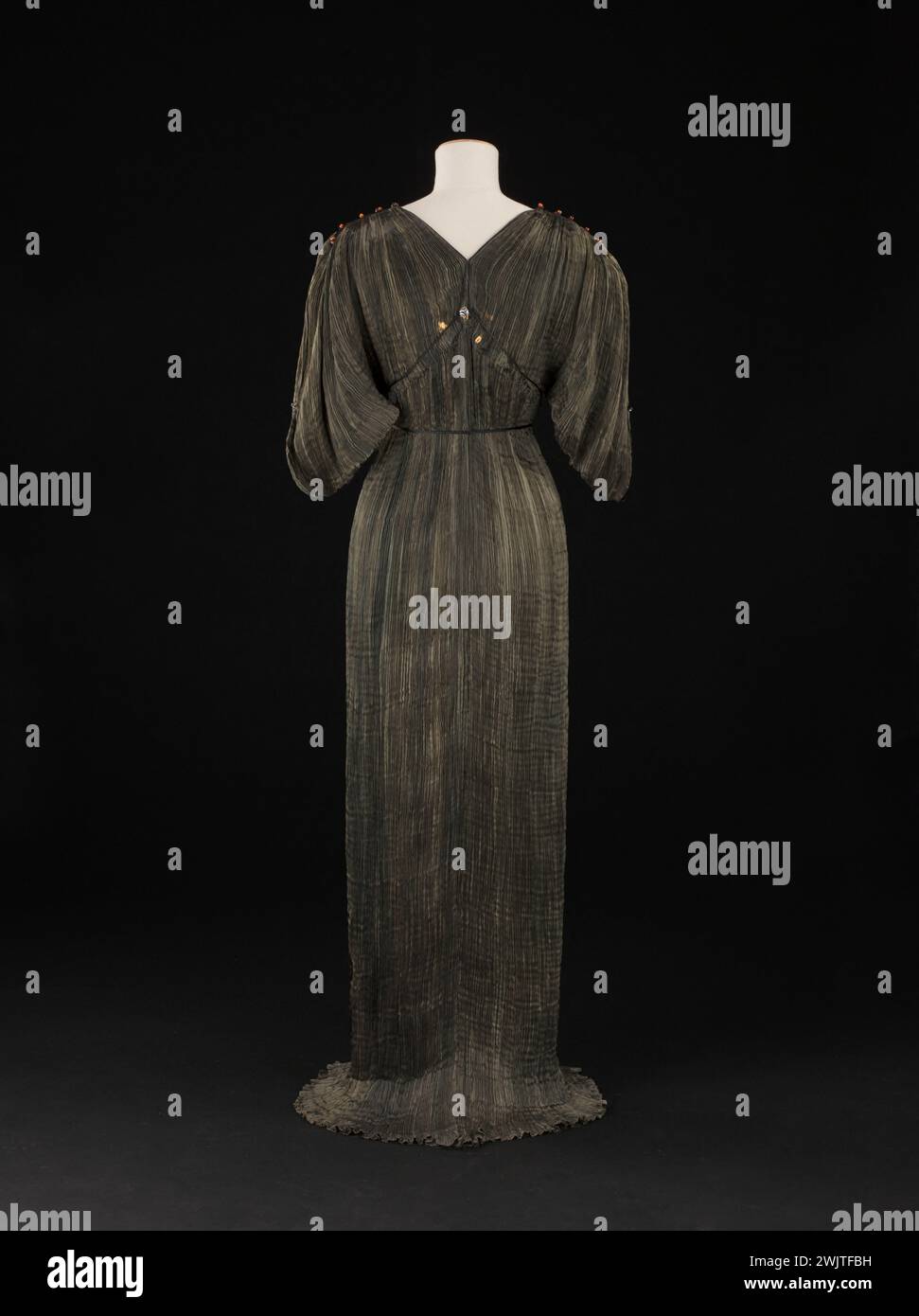 Mariano Fortuny (1871-1949). Delphos-Kleid. Bronzegrüne Seide, schwarzes Seidengeschäft, bernsteinfarbene Glasperlen, weiße und schwarze Glasperlen. Etwa 1912-1919. Galliera, Modemuseum der Stadt Paris. 101979-13 Haute Couture, weiblicher Modus, weibliches Modell Stockfoto