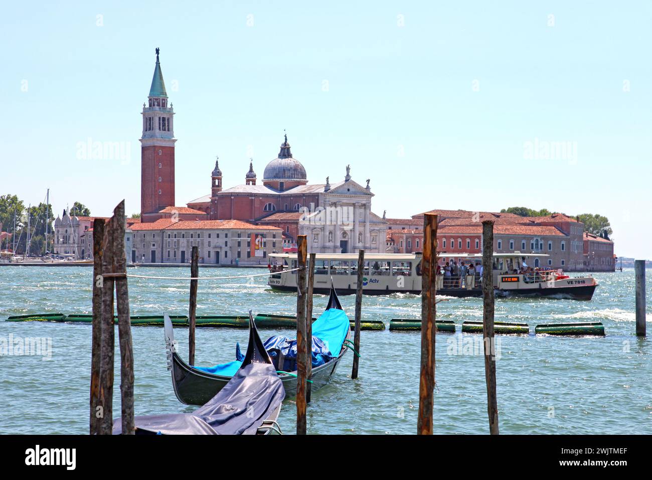 Kirche San Giorgio Maggiore und St. George Bell Tower in der Ferne mit Gondeln im Vordergrund in Venedig, Italien. Stockfoto