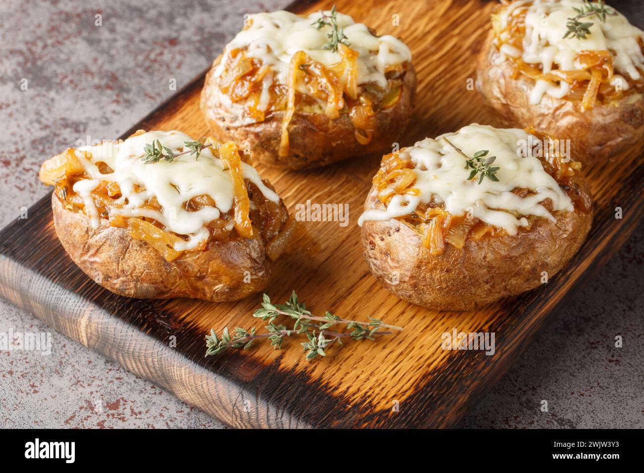 Gebackene Kartoffeln gefüllt mit karamelisierten Zwiebeln und Gruyerekäse in einer Schüssel auf dem Tisch. Horizontal Stockfoto