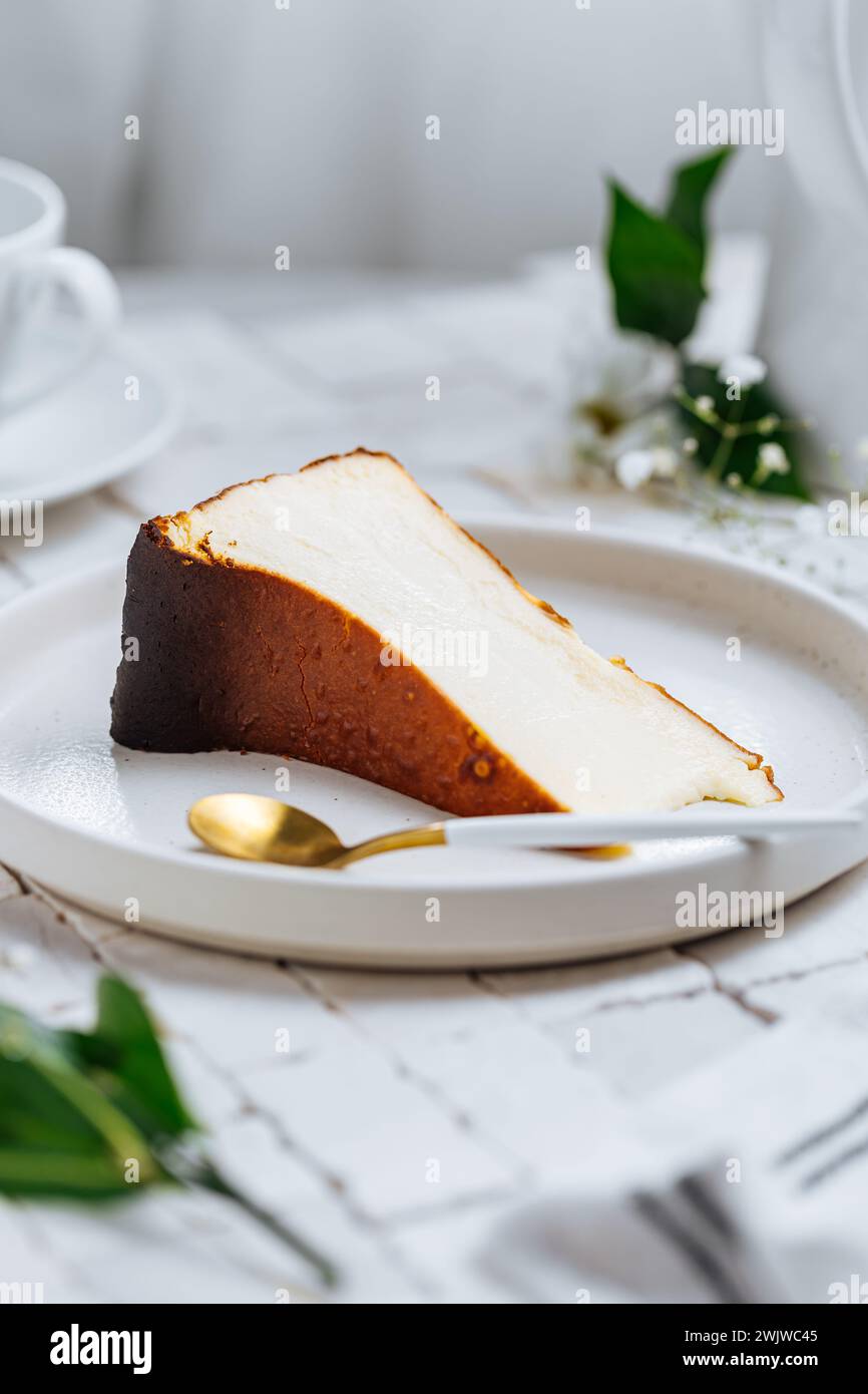 Beliebtes spanisches Dessert namens San Sebastian Käsekuchen. Klassischer baskischer Käsekuchen mit verbranntem Käse. Ein Stück Kuchen auf weißem Hintergrund Stockfoto