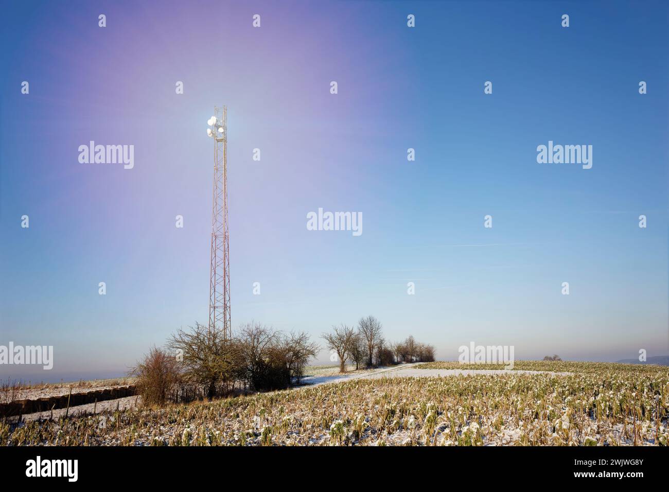 5G-Funkrelais-Antenne auf einem schneebedeckten Feld. Die Strahlung wird durch transparente Objekte symbolisiert. Stockfoto