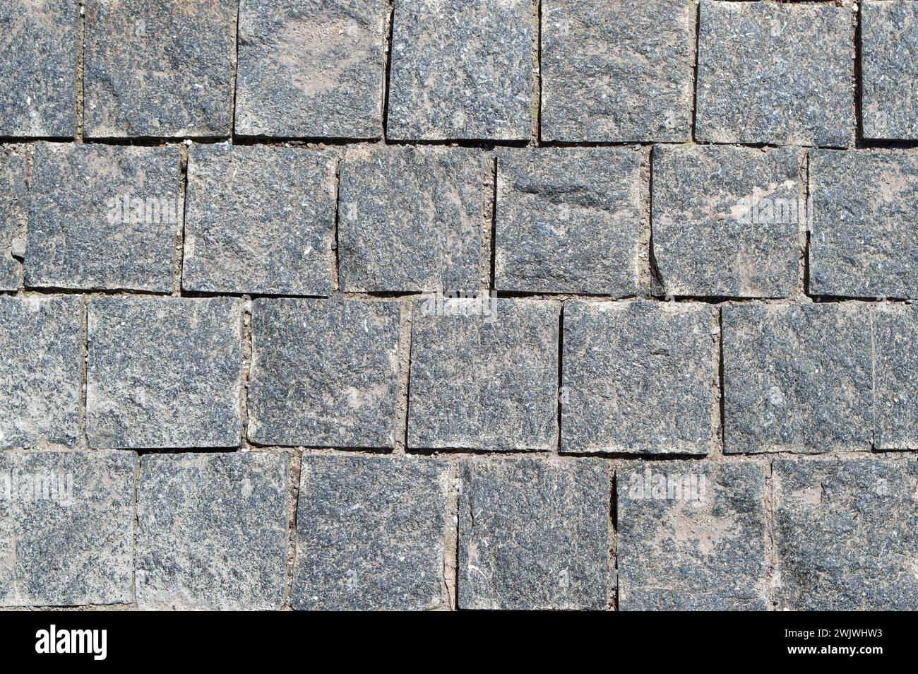 Kopfsteinpflasterhintergrund aus Granit, regelmäßige Formen von Kopfsteinpflasterpfaden, abstrakter Hintergrund des alten Kopfsteinpflasterpflasterpflasterpflasterpflasterpflasterpflasterpflasterpflasterpflasterpflasterpflaster Stockfoto