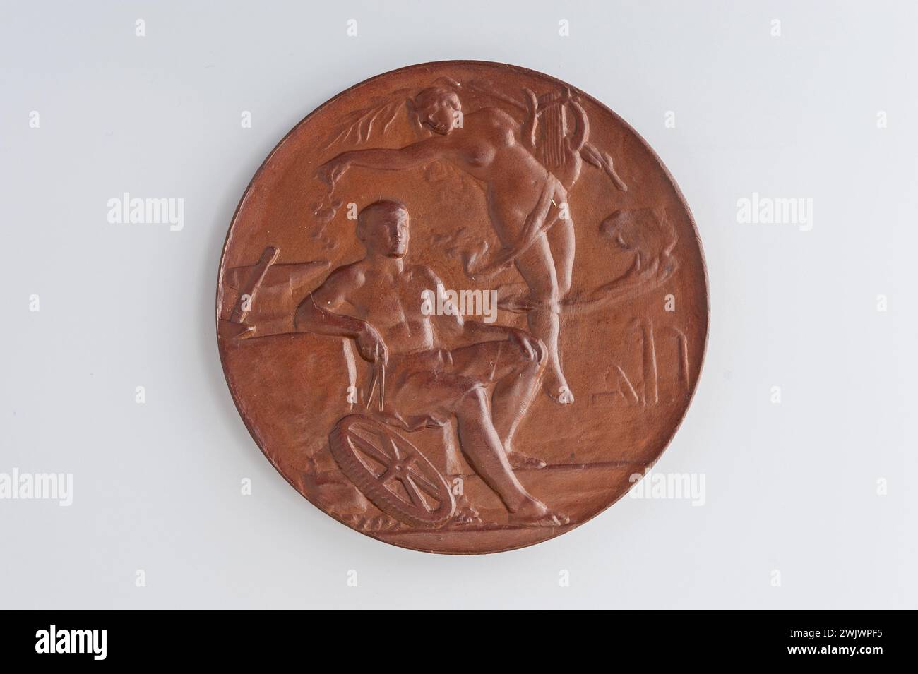 Museum Carnavalet, Medaillensammlung rechts die Allegorie der Künste, die von den Wolken hochgehoben sind, links eine Leier und eine Palme hält, fällt eine Rose über dem Kopf eines Arbeiters, der zu drei Vierteln rechts sitzt und sich auf einen Amboss stützt, gegen den ein Hammer steht. rechts einen Kompass halten; zu seinen Füßen ein Zahnrad; hinten rechts eine Fabrik mit Rauchschornsteinen; umgekehrte Schilde zu den Armen von Charleroi, die einen Schild mit den Armen von Lüttich auf einem Lorbeerzweig anlegen; unter einem glatten Band. Stockfoto