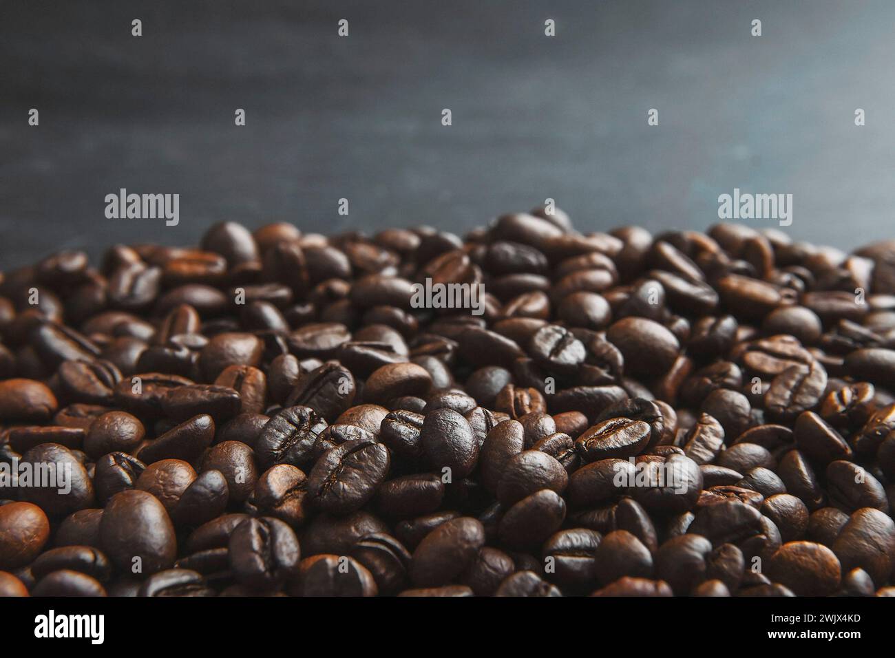 Geröstete Kaffeebohnen auf einem Steinhintergrund. Kaffeebohnen-Textur. Kaffee in Bohnen auf dunklem Hintergrund. Lebensmittelhintergrund von Kaffeebohnen. Abstrakter Backgr Stockfoto