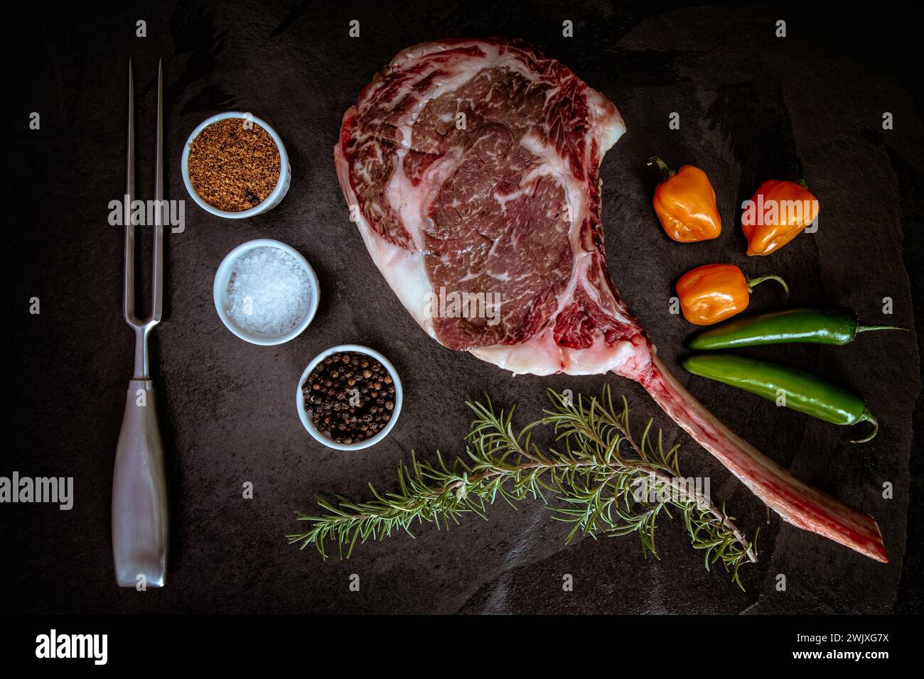 Wagyu Tomahawk Steak auf Schiefergrund mit Salz, Pfeffer, Rosmarin und Paprika Stockfoto