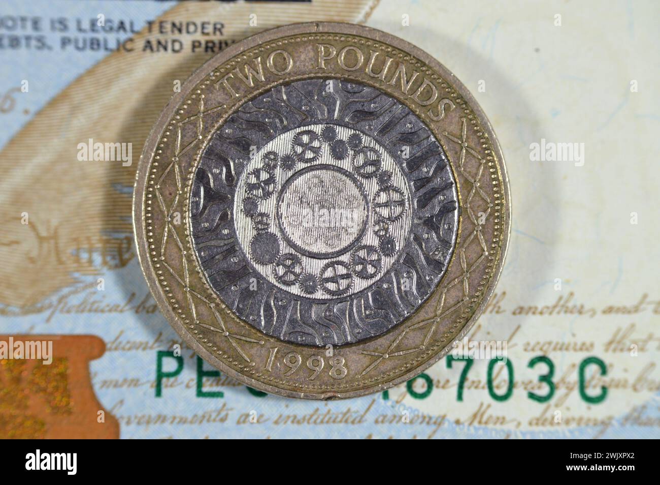 US-Dollar und zwei britische Pfund-Münze mit Königin Elizabeth II. Auf der Vorderseite und vier konzentrischen Kreisen für die Eisenzeit, Industrial Revo Stockfoto