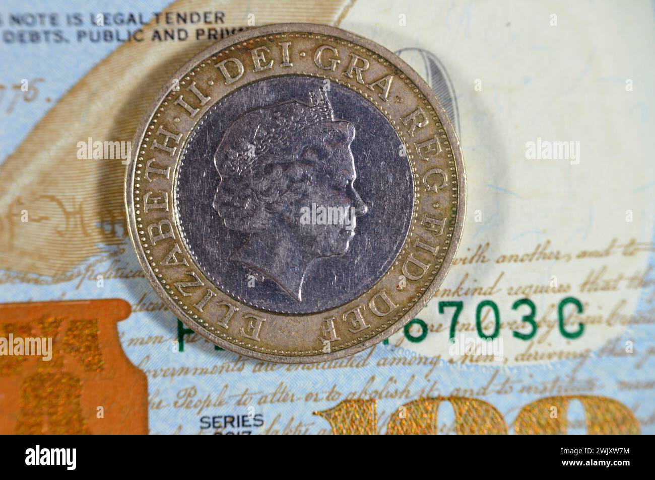 US-Dollar und zwei britische Pfund-Münze mit Königin Elizabeth II. Auf der Vorderseite und vier konzentrischen Kreisen für die Eisenzeit, Industrial Revo Stockfoto