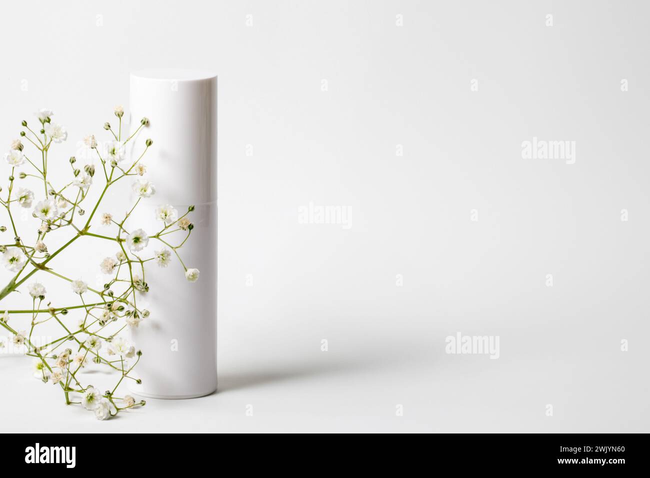 Weiße Creme Tube mit kleinen weißen Blüten isoliert auf weißem Hintergrund. Hautpflegekonzept Stockfoto