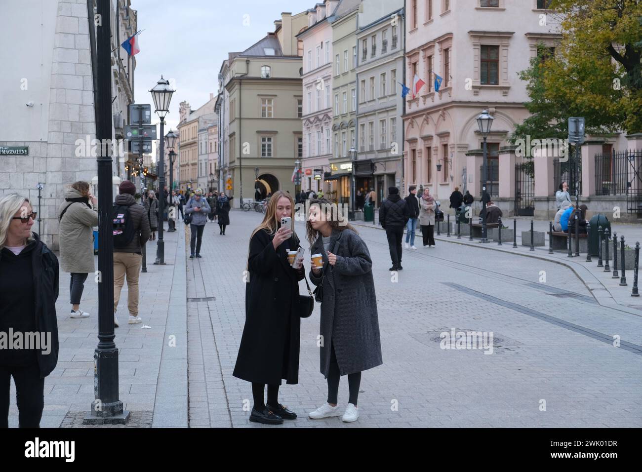 Zwei Frauen mit Kaffee schauen sich ein Telefon in der Grodzka Straße im alten Krakau an Stockfoto