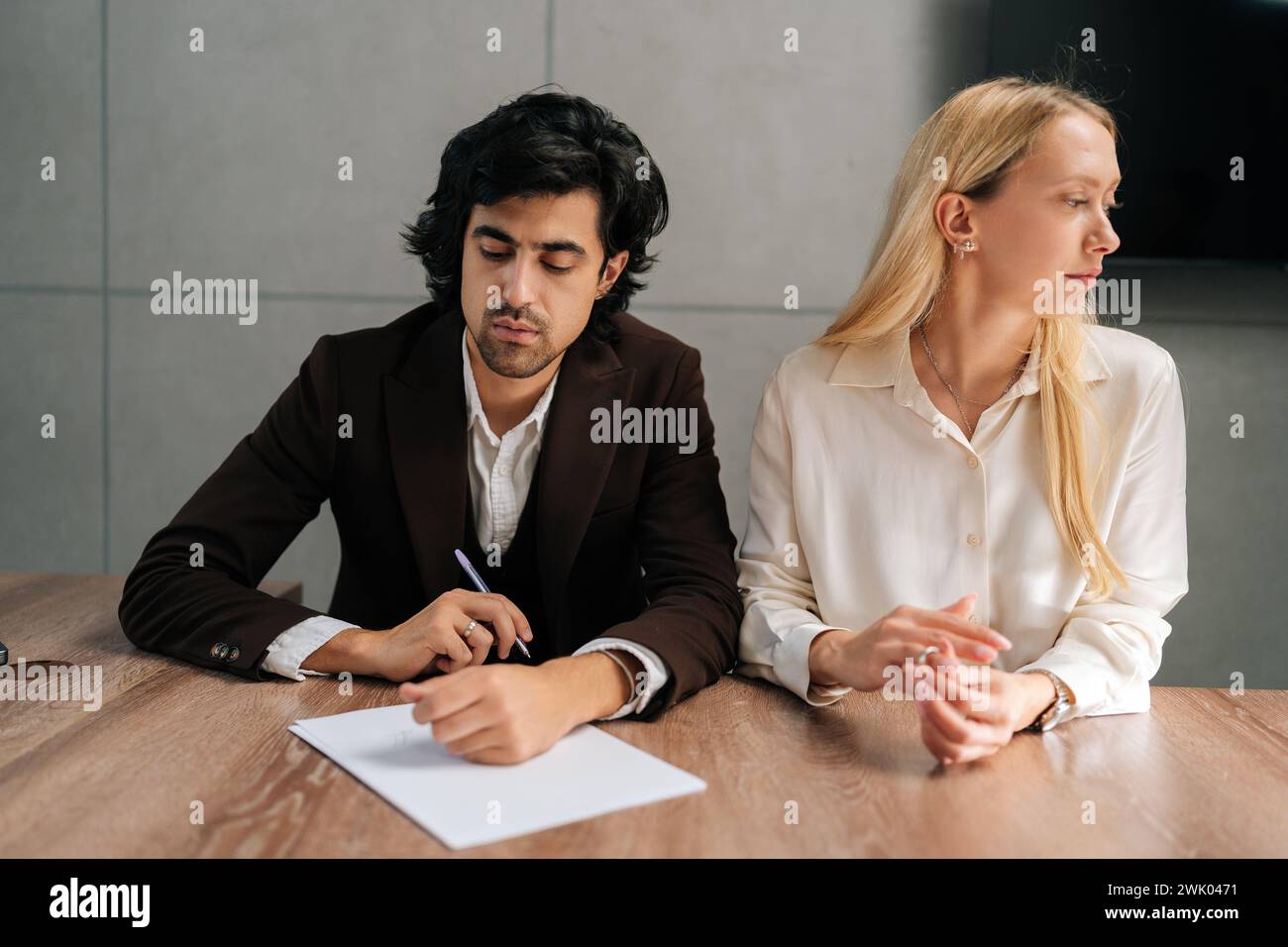 Porträt von traurigen Ehepaaren, die Dekrete unterzeichnen und sich im Büro der Anwälte am Schreibtisch scheiden lassen. Unglücklicher verheirateter Mann und Frau, die Scheidung einreichen, Aktien Stockfoto