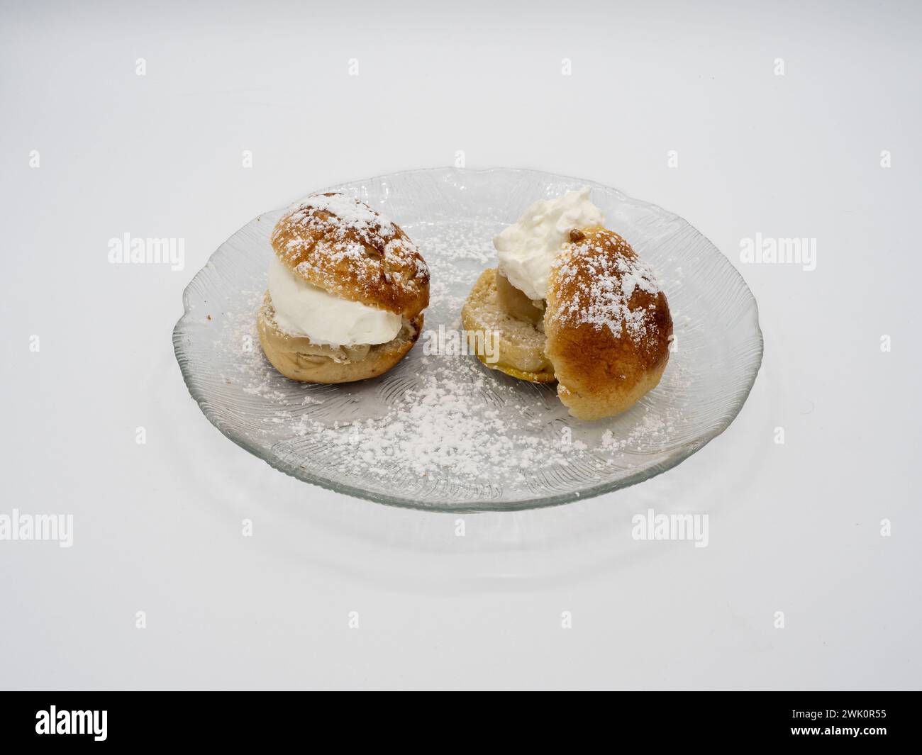 Eine Seitenperspektive einer klassischen schwedischen Semla, auch bekannt als Fastlagsbulle, verziert mit Schlagsahne, Mandelpaste und Puderzucker, elegant PR Stockfoto