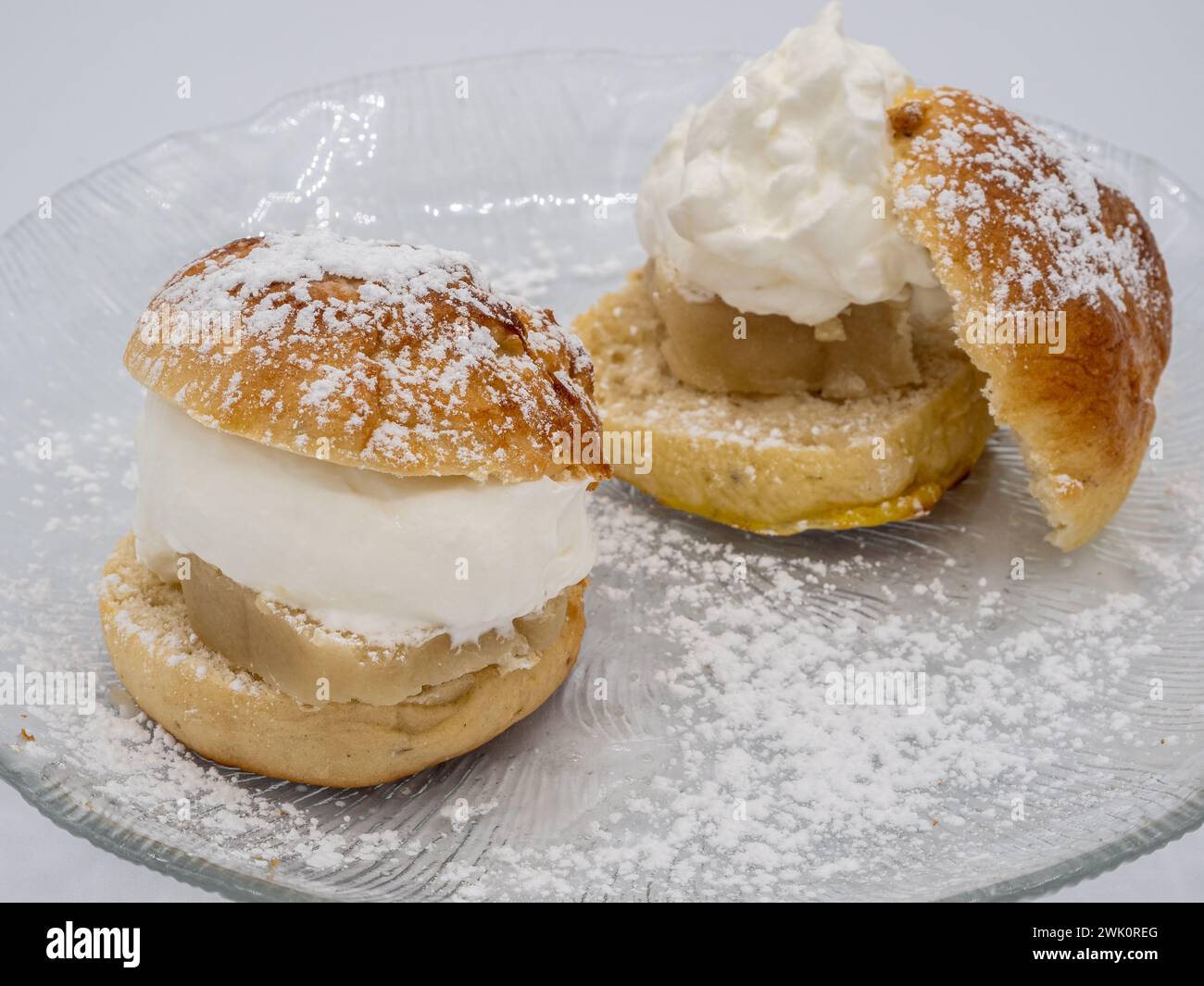 Detaillierte Seitenaufnahme einer klassischen schwedischen Semla, auch bekannt als Fastlagsbulle, verziert mit Schlagsahne, Mandelpaste und Puderzucker Stockfoto