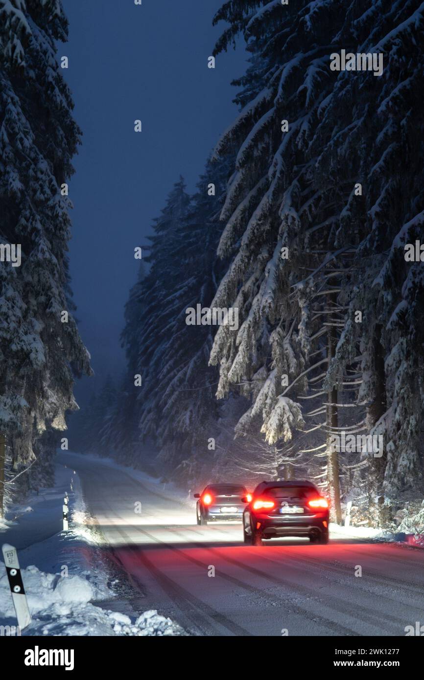 Roter Sportwagen, der nachts auf verschneiten Landstraßen fährt Stockfoto