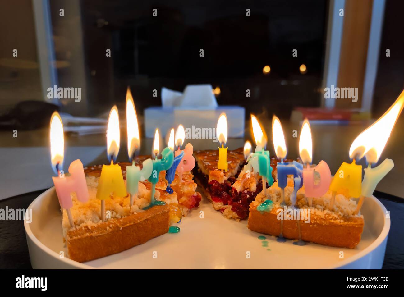 Unordentliche Geburtstagskuchen bunte bunt brennende und schmelzende Happy Birthday Kerzen auf Kuchenscheiben, die auf einem Teller ausgestellt werden, machen ein Happy Birthday Chaos. Stockfoto
