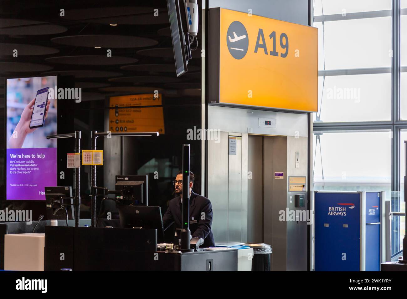 Ein Flugsteigeragente von British Airways arbeitet an seinem Computer am Flugsteig A19 in Terminal 5 am Flughafen Heathrow in London, England. Stockfoto