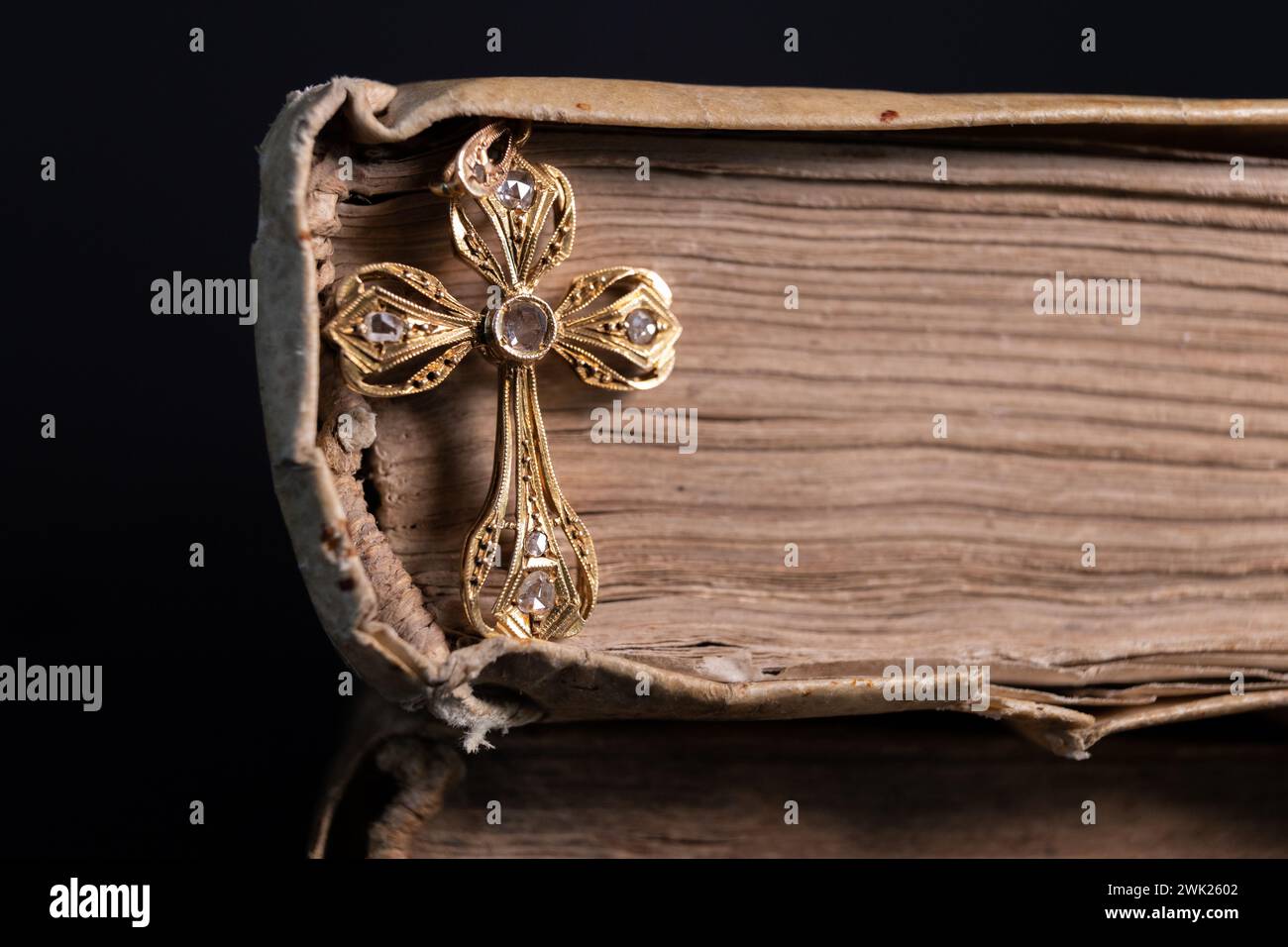 Ein Gold- und Diamantkreuz in einem alten Buch, wunderschön beleuchtet Stockfoto
