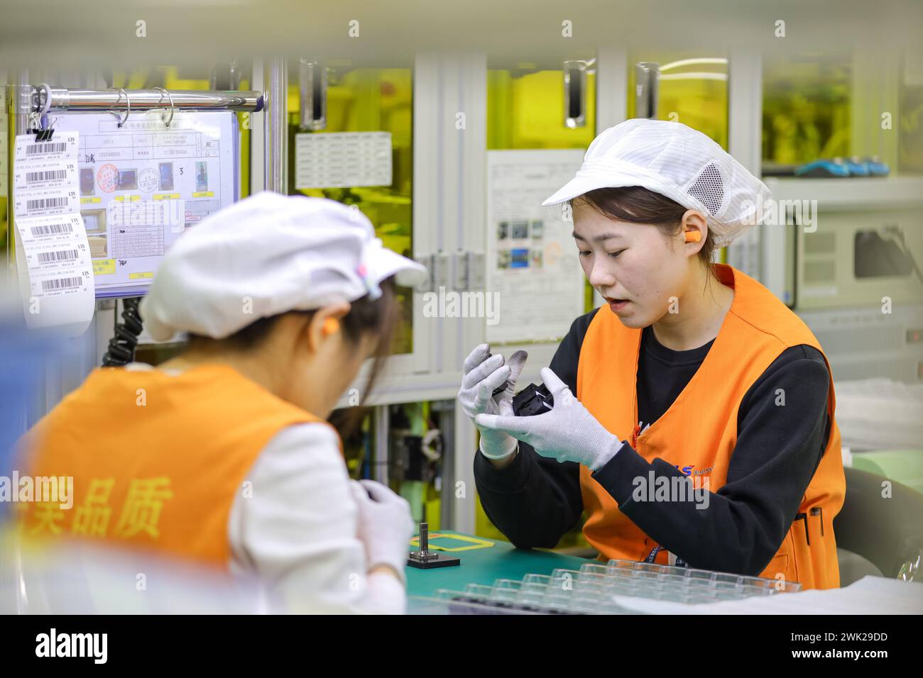 QINGDAO, CHINA - 18. FEBRUAR 2024 - zwei Arbeiter führen Inspektions- und Verpackungsarbeiten in einer Werkstatt eines Automobilelektronikunternehmens in Q durch Stockfoto