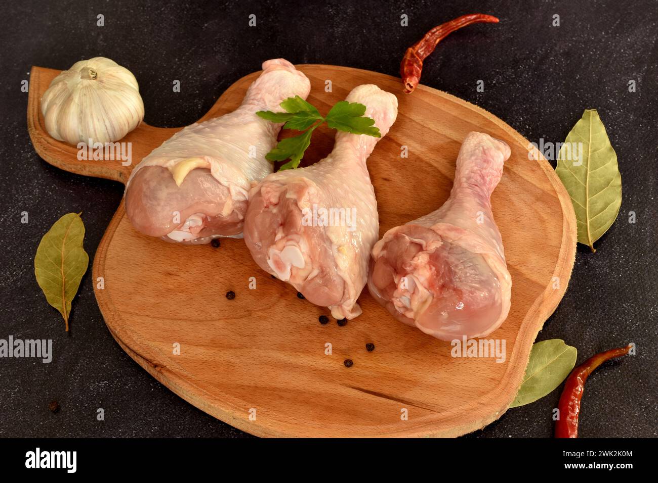 Auf dem Schneidebrett befinden sich drei Hähnchenschenkel, die zum Kochen bereit sind. Stockfoto