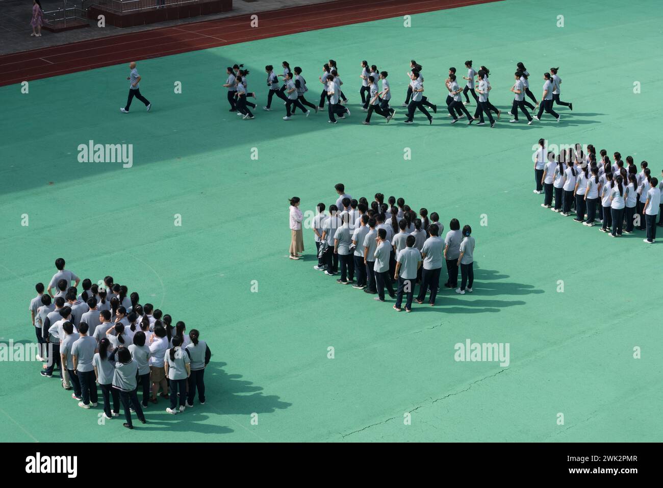 In einer Mittelschule in Shanghai leitet ein Lehrer eine Klasse von Schülern, um die Eröffnungszeremonie auf dem Spielplatz zu Proben Stockfoto