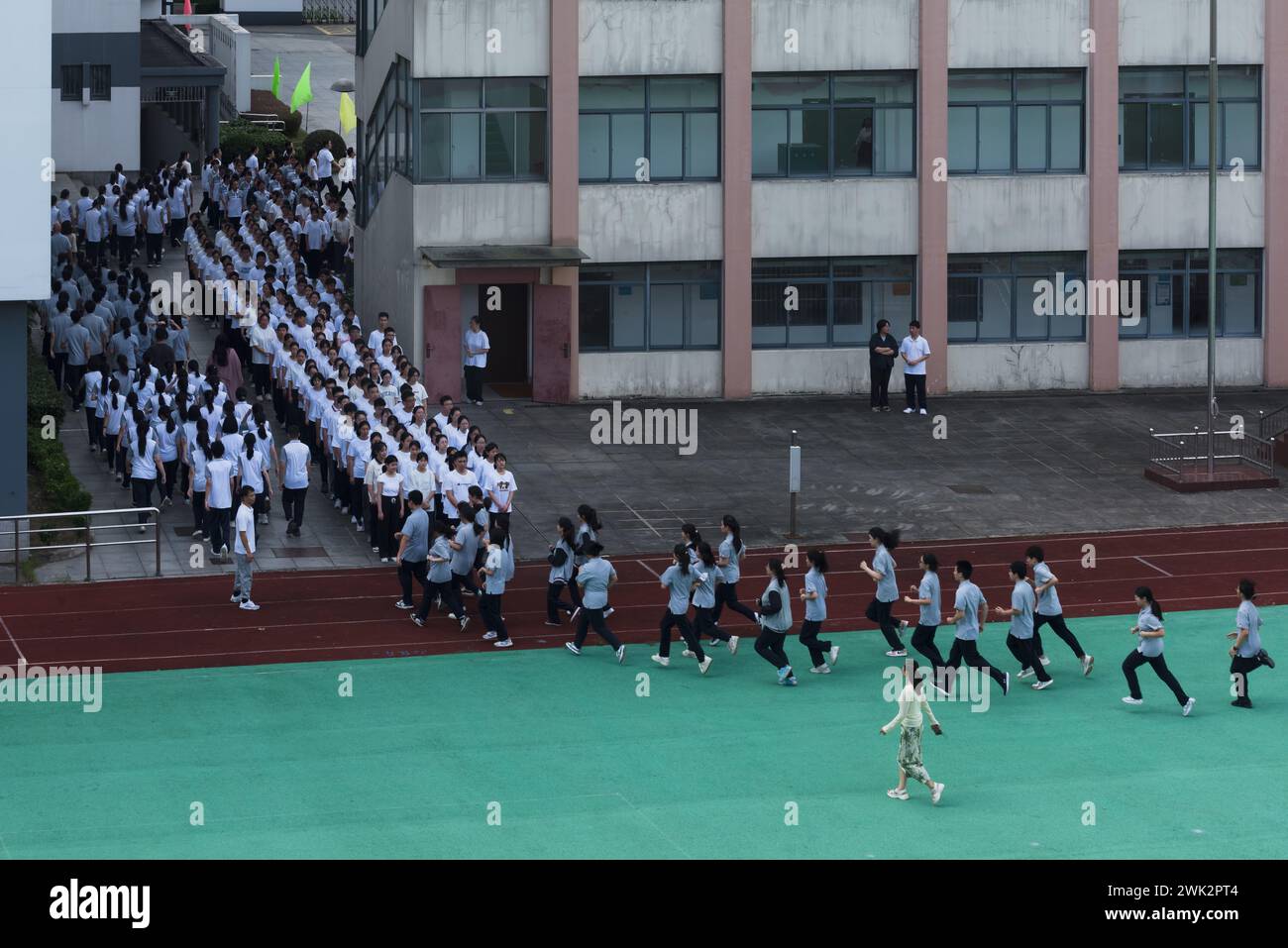 In einer Mittelschule in Shanghai leitet ein Lehrer eine Klasse von Schülern, um die Eröffnungszeremonie auf dem Spielplatz zu Proben Stockfoto
