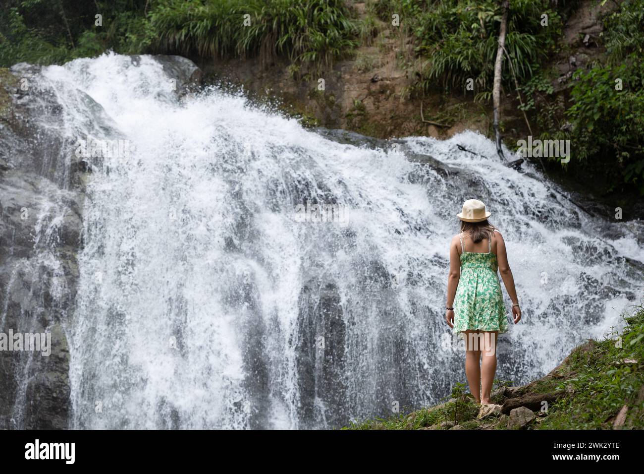 Eine Reisende Frau denkt über einen Wasserfall im peruanischen Dschungel nach. Stockfoto