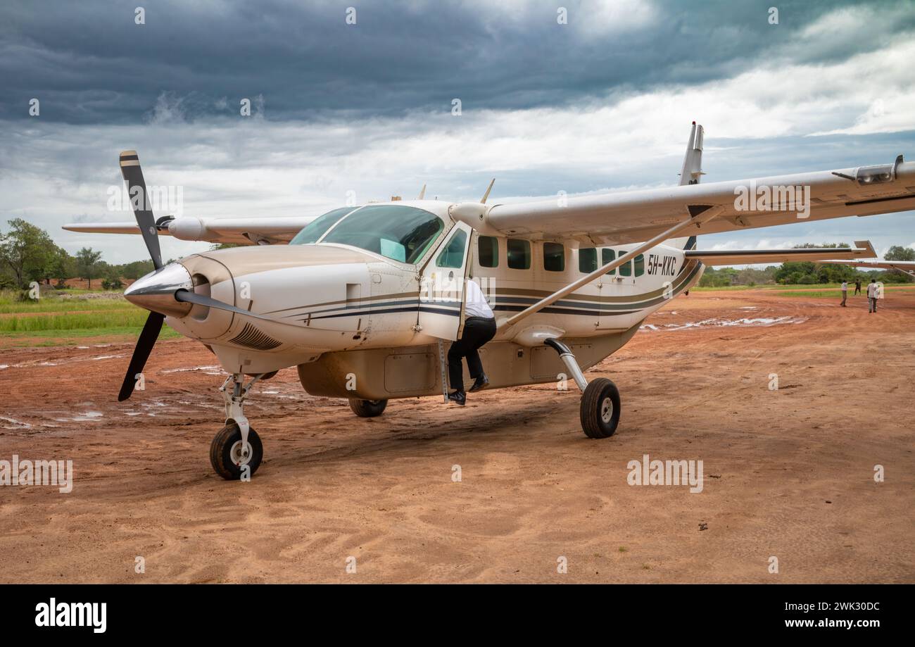 Ein Pilot steigt in einem 12-sitzigen Cessna-Leichtflugzeug von Auric Air Services auf dem Mtemere-Flugplatz im Nyerere-Nationalpark (Selous GA) in das Cockpit Stockfoto