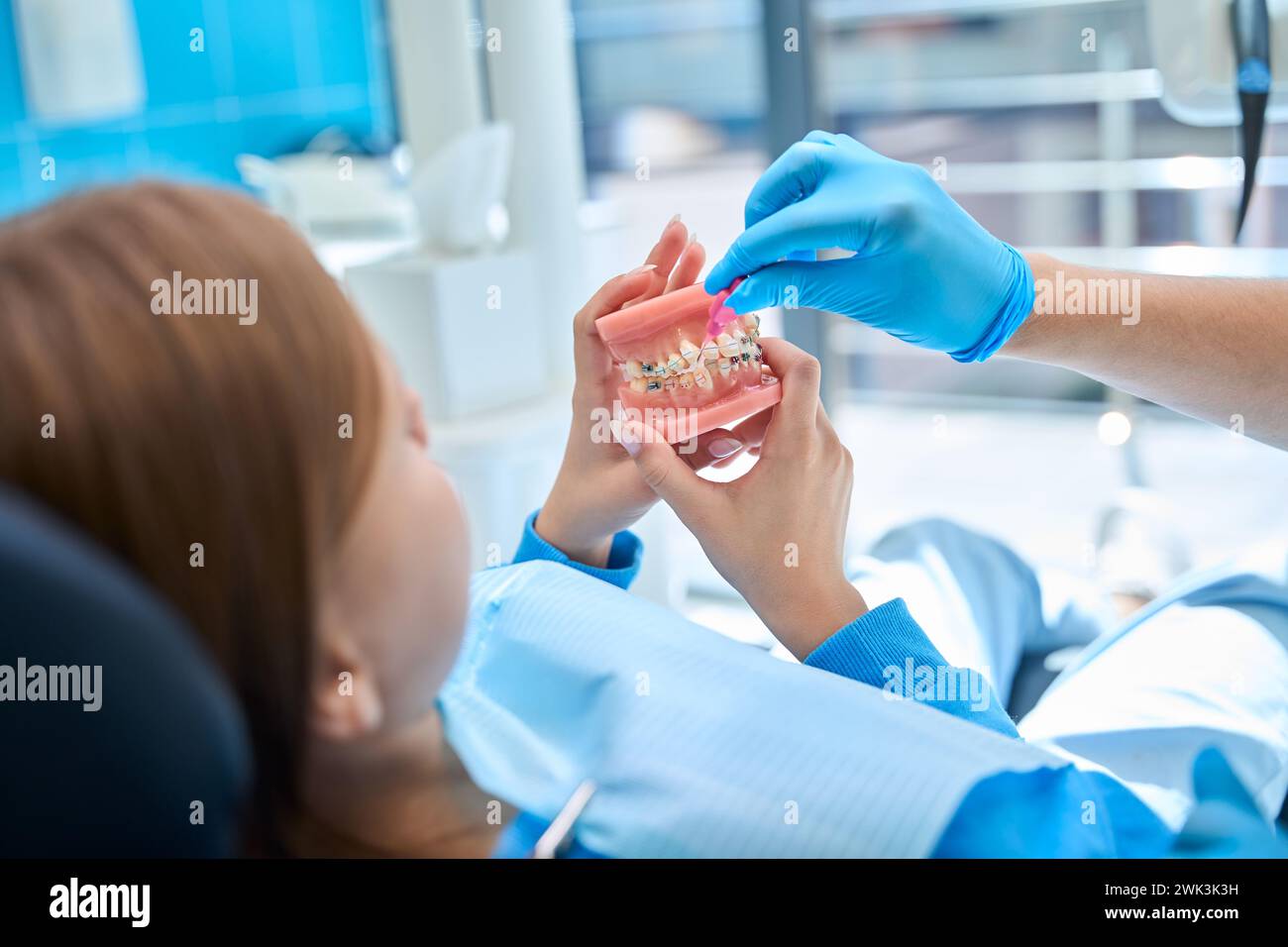 Der Kieferorthopäden lehrt das Kind, sich um die Mundhöhle zu kümmern, wenn er eine Zahnspange trägt Stockfoto