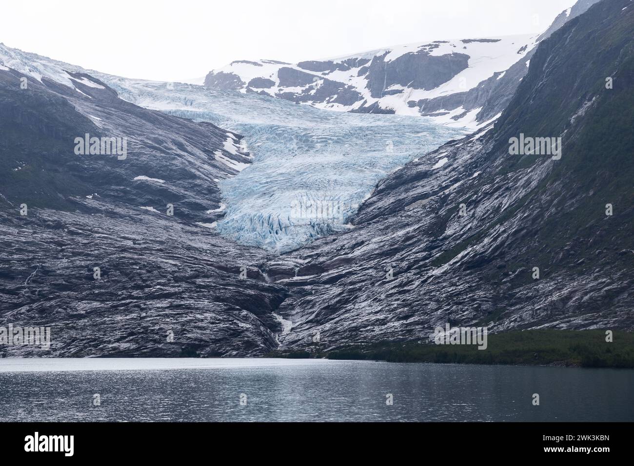 Ein ruhiger See am Fuße des Svartisen-Gletschers, der das schwindende Licht inmitten der rauen Schönheit der arktischen Wildnis reflektiert Stockfoto