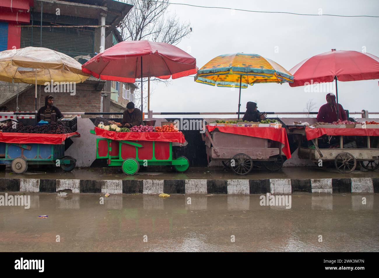 Straßenhändler warten während des Niederschlags an einem kalten Wintertag in Srinagar, der Sommerhauptstadt von Jammu und Kaschmir, auf Kunden. In den höheren Regionen Kaschmirs kam es zu neuem Schneefall und in den Ebenen der Region kam es zu Regenfällen, die die Temperaturen um mehrere Grad senkten. Das meteorologische Amt hat in den nächsten Tagen aufgrund der starken westlichen Störungen im Tal starke bis mäßige Schneefälle vorhergesagt. Stockfoto