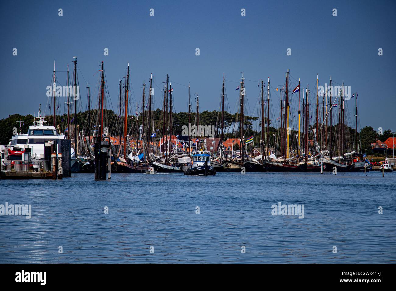 Eine Flotte von Booten, die an einem Dock vorbeischwimmen, umgeben von anderen Schiffen Stockfoto