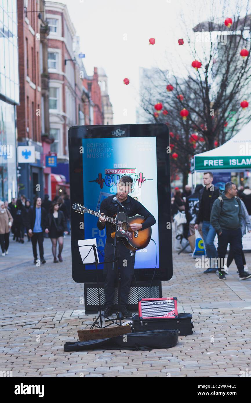 Ein Straßenmusiker spielt Gitarre und singt in der Market Street Manchester Stockfoto