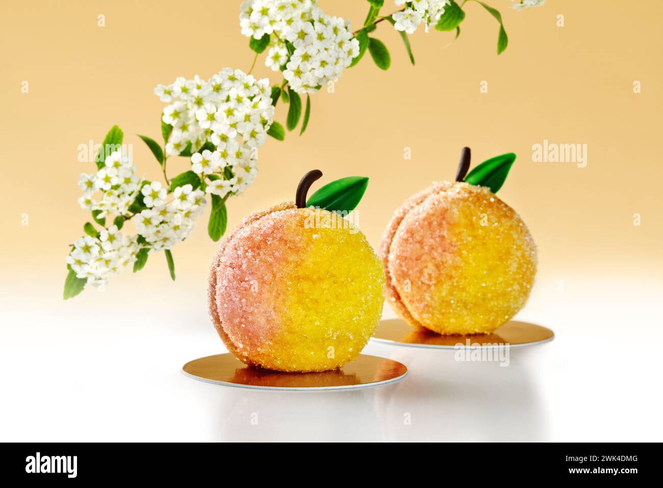 Gezuckertes pfirsichförmiges Gebäck vor warmer Kulisse mit blühendem Baum Stockfoto