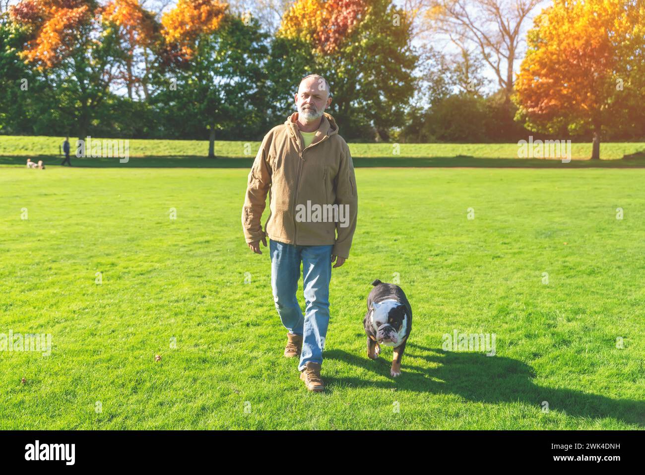 Ein alter Mann, der mit seinem Hund im Park läuft Stockfoto