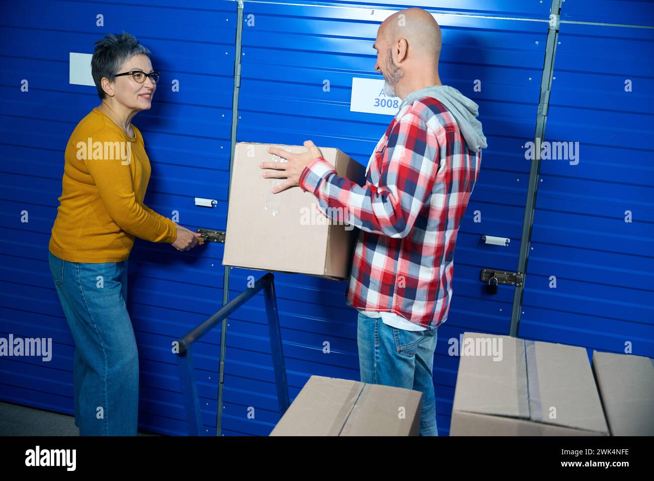 Frau öffnet die Tür, während ein Mann in der Nähe steht Stockfoto
