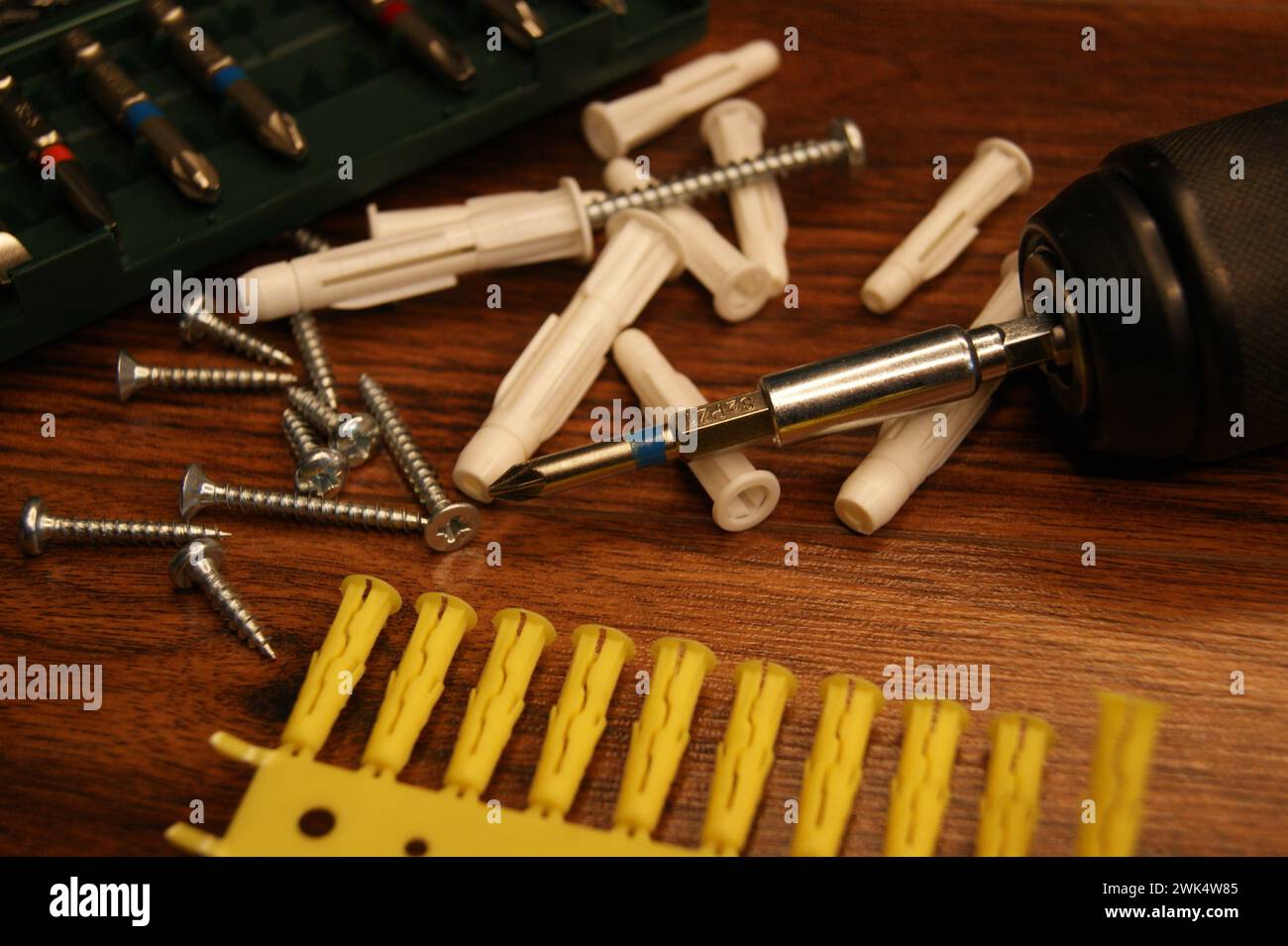 Dübel, Schrauben, Schraubendreher, Bitsatz. Ein Chaos im Montageprozess auf dem Tisch. Stockfoto