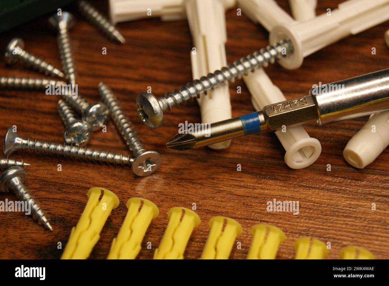 Dübel, Schrauben, Bohrer. Ein Chaos im Montageprozess auf dem Tisch. Stockfoto