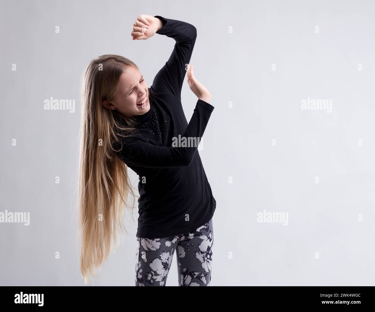 Das junge Mädchen hebt wehrhaft die Arme und grimmt, als wolle es etwas Abstoßendes oder Furcht abwehren Stockfoto