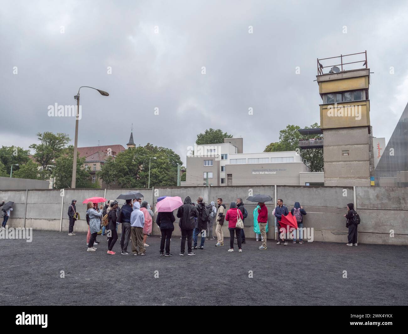 Tourgruppe auf dem erhaltenen Abschnitt der Berliner Mauer in der Bernauer Straße gegenüber dem Dokumentationszentrum, Berlin, Deutschland. Stockfoto